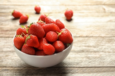 Bowl with fresh ripe strawberries on wooden table