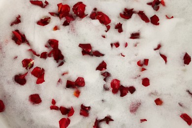Photo of Foam and red rose petals as background, top view. Relaxing bath