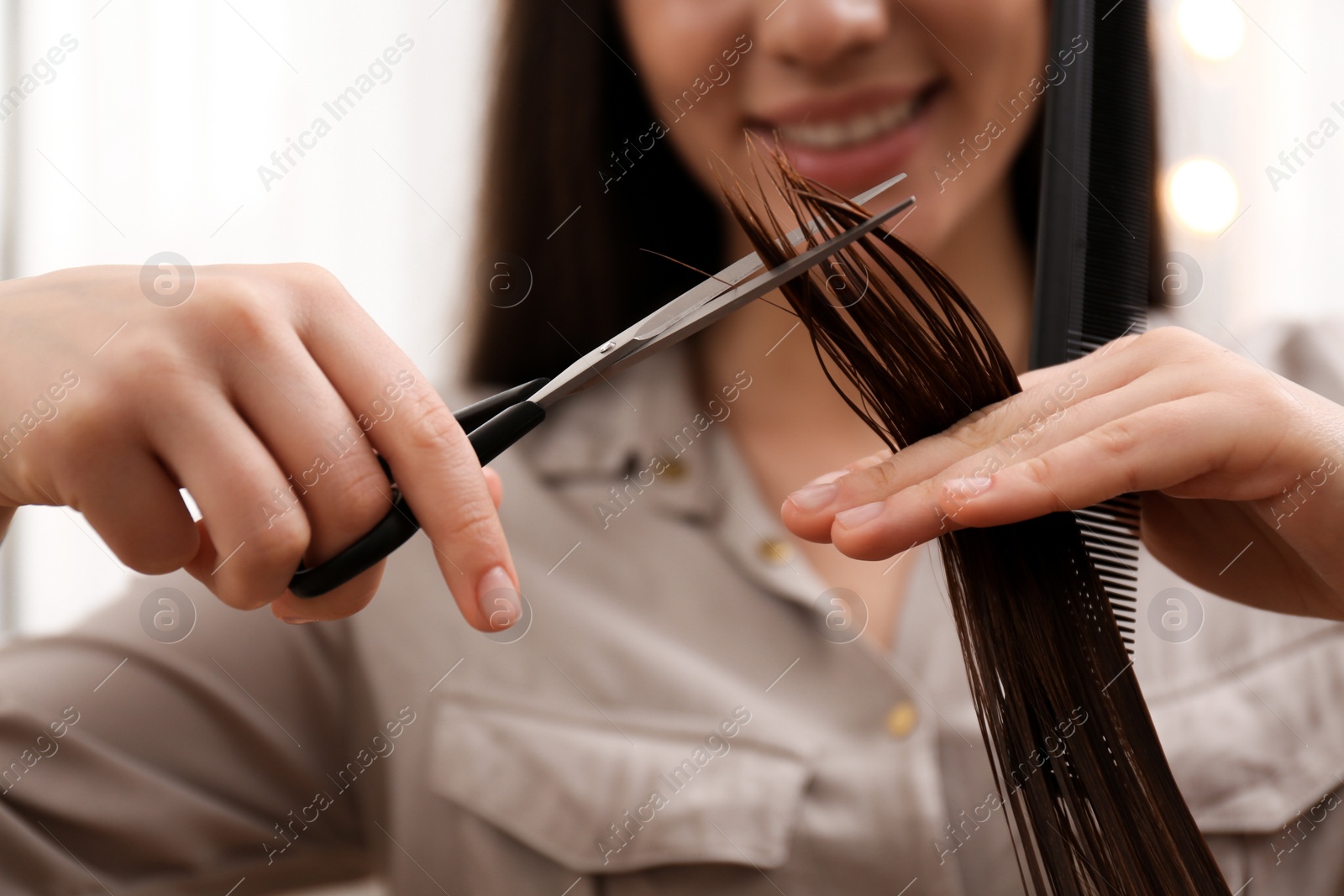 Photo of Stylist cutting hair of client in professional salon, closeup