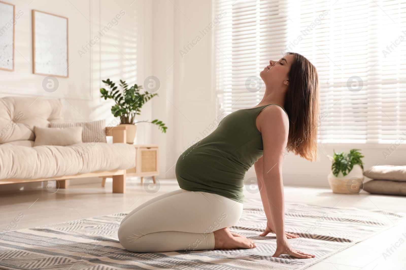 Photo of Young pregnant woman practicing yoga at home