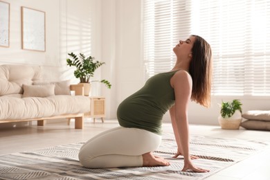 Photo of Young pregnant woman practicing yoga at home