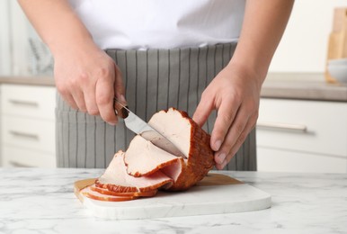 Photo of Man cutting delicious ham at white marble table indoors, closeup