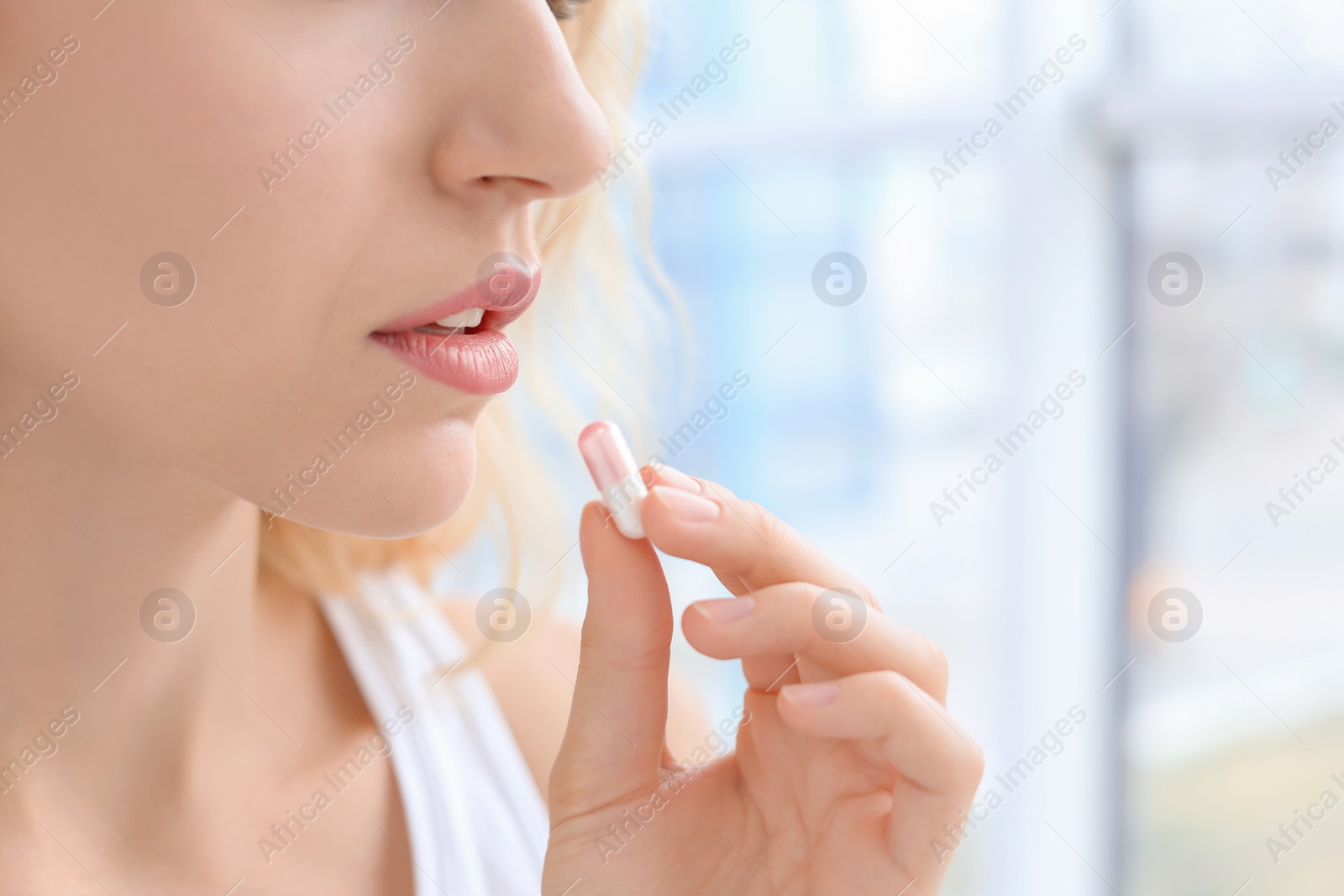 Photo of Young woman taking pill indoors