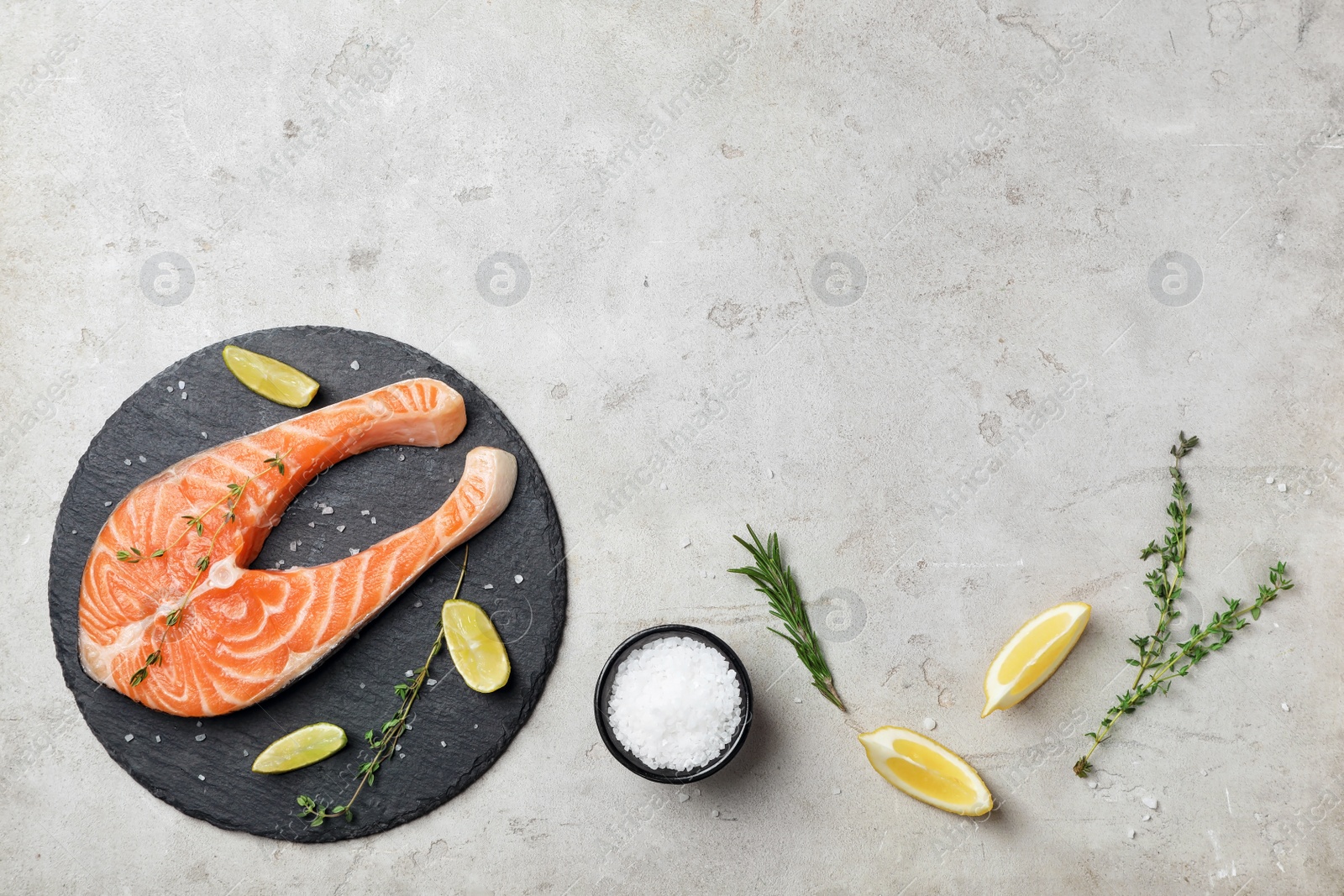 Photo of Slate plate with fresh raw salmon steak on gray background, top view