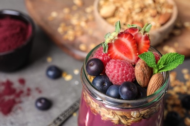 Delicious acai dessert with granola and berries served on grey table, closeup