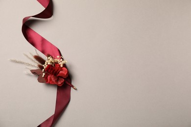 Stylish boutonniere and red ribbon on light grey background, top view. Space for text