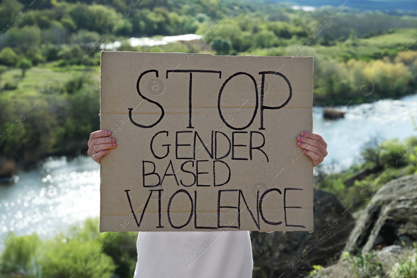 Photo of Woman holding sign with text Stop Gender Based Violence outdoors