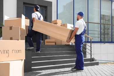 Photo of Male movers carrying shelving unit into new house