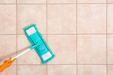 Photo of Janitor cleaning floor with mop, top view. Space for text