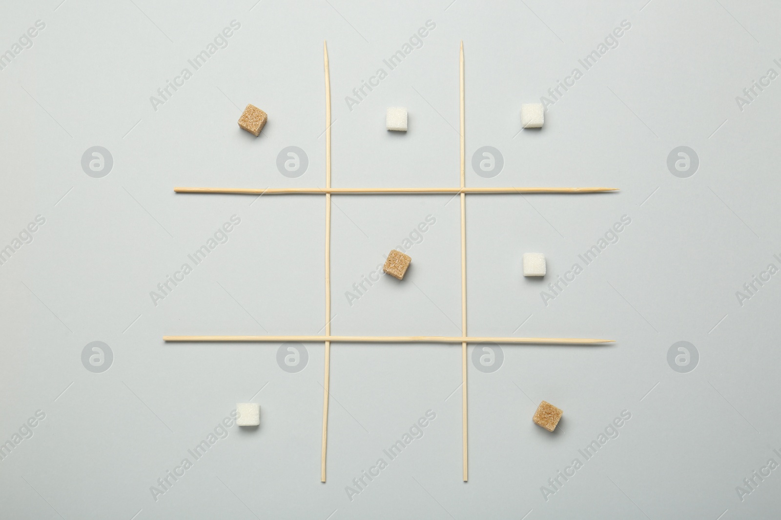 Photo of Tic tac toe game made with sugar cubes on light background, top view