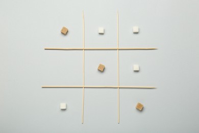 Photo of Tic tac toe game made with sugar cubes on light background, top view