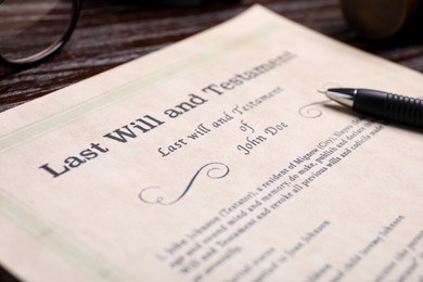 Photo of Last will and testament with pen on wooden table, closeup