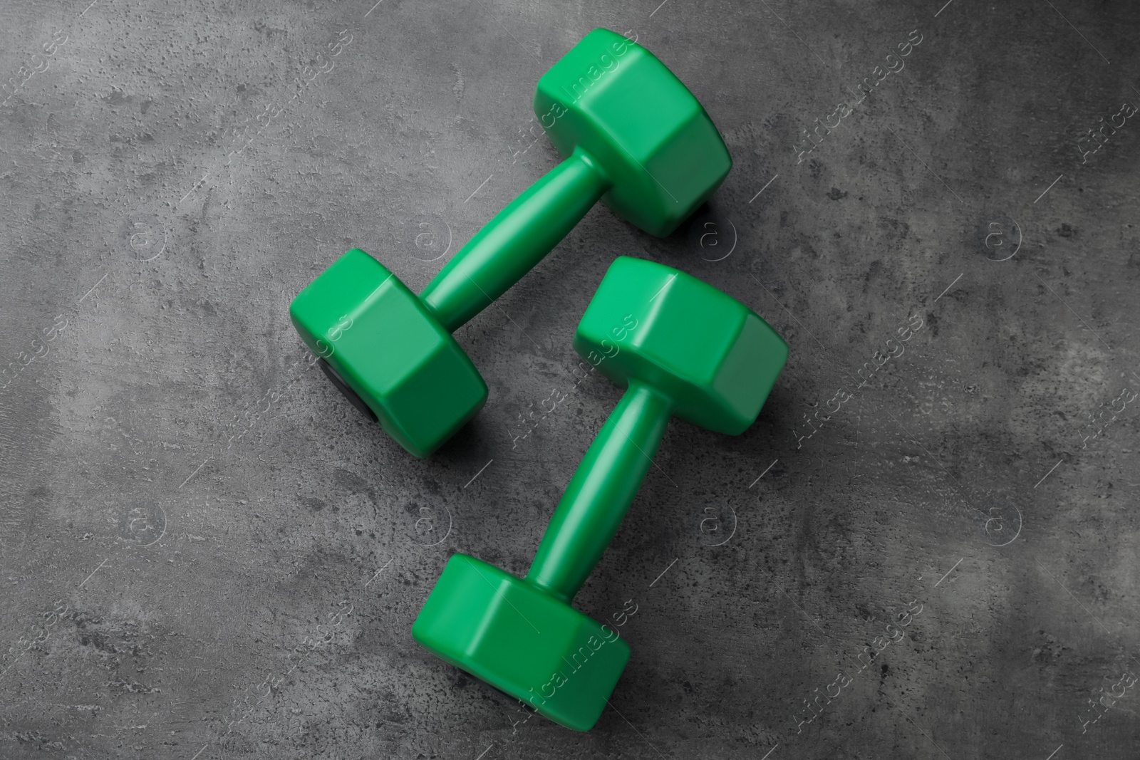 Photo of Two green dumbbells on grey table, flat lay