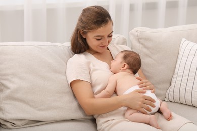 Photo of Mother holding her cute newborn baby on sofa indoors