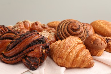 Photo of Different tasty freshly baked pastries on white tablecloth, closeup