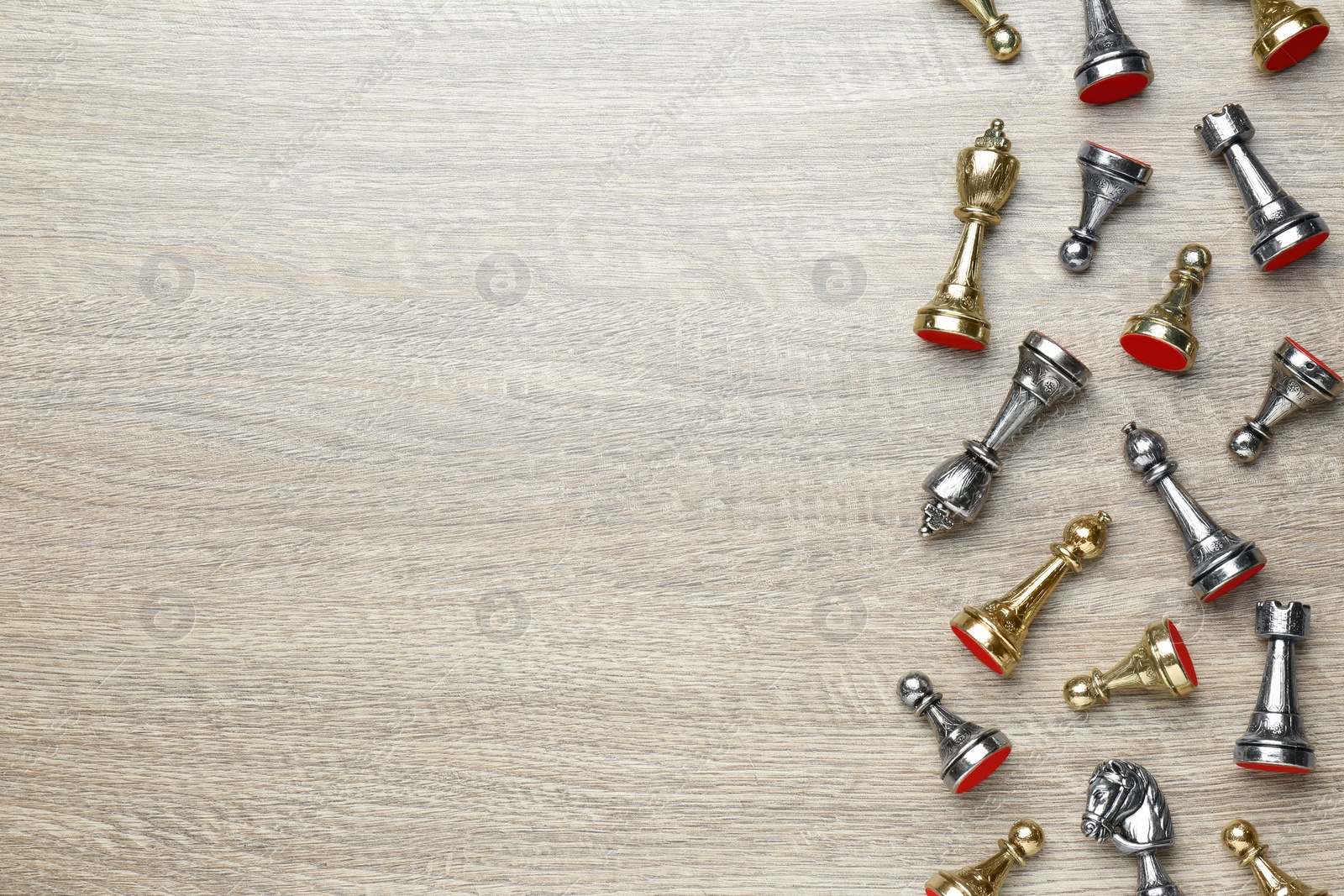 Photo of Silver and golden chess pieces on wooden table, flat lay. Space for text