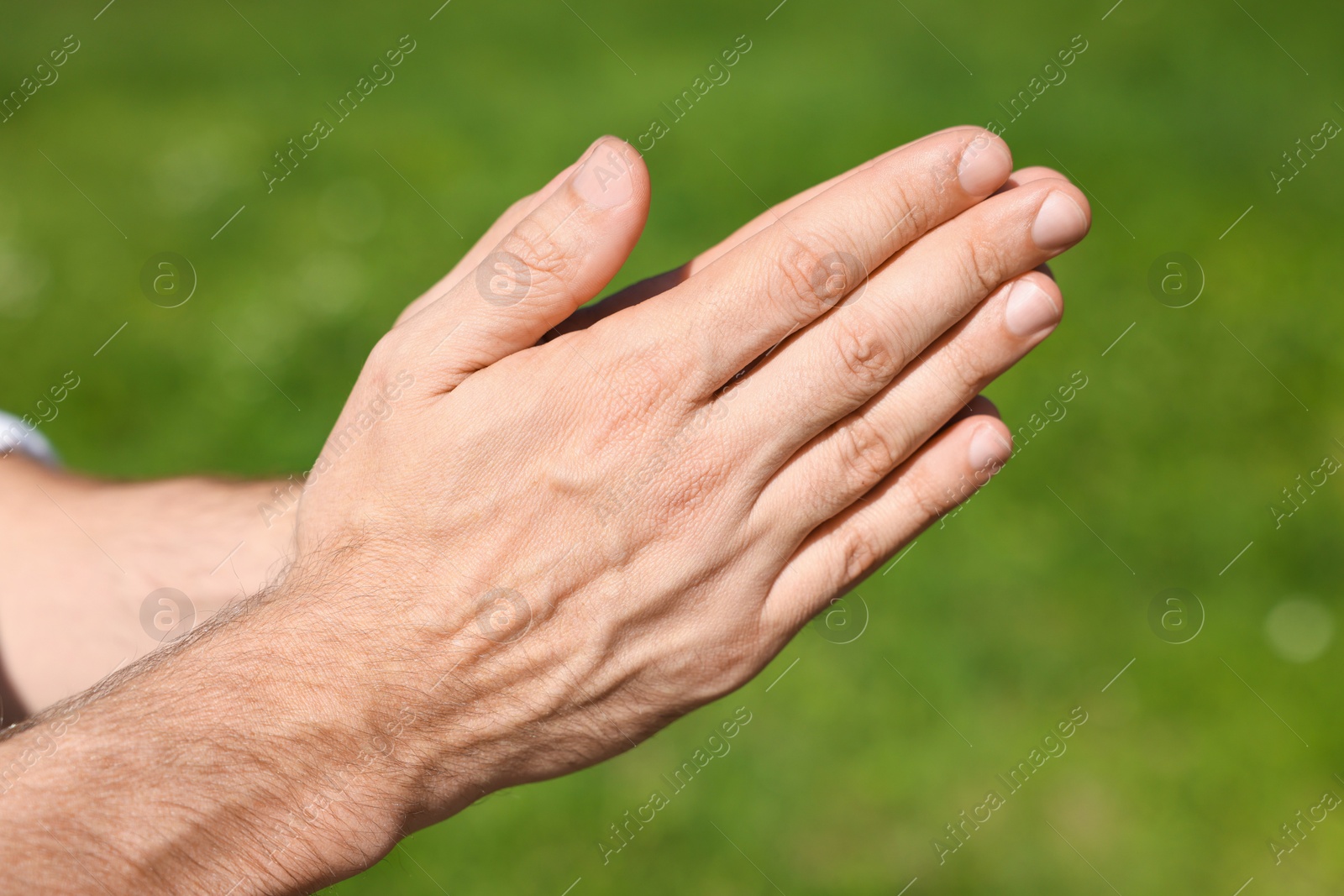 Photo of Man praying outdoors on sunny day, closeup