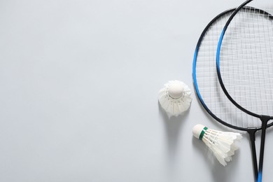 Feather badminton shuttlecocks and rackets on gray background, flat lay. Space for text