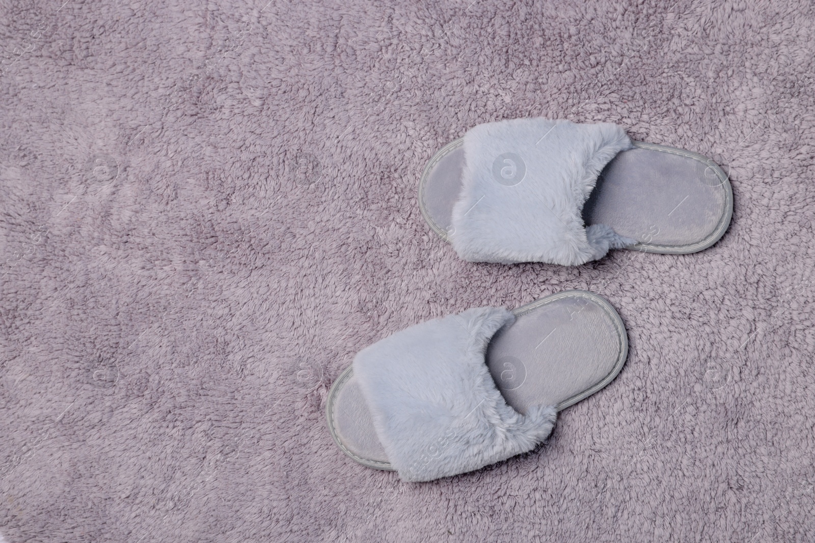 Photo of Soft slippers on grey fluffy carpet, top view. Space for text