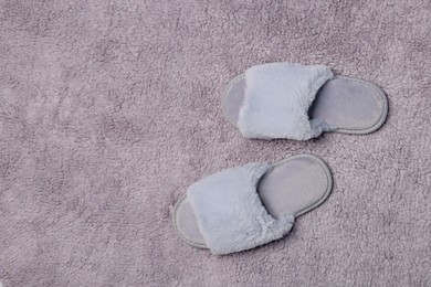 Soft slippers on grey fluffy carpet, top view. Space for text