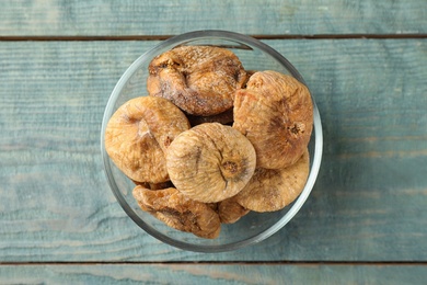 Glass bowl of dried figs on light blue wooden table, top view