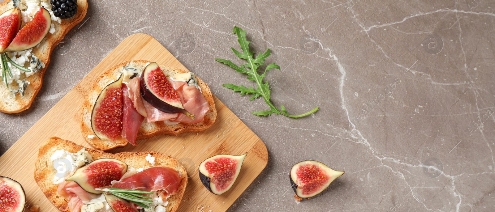 Image of Bruschettas with cheese, prosciutto and figs on marble table, top view. Space for text, banner design 