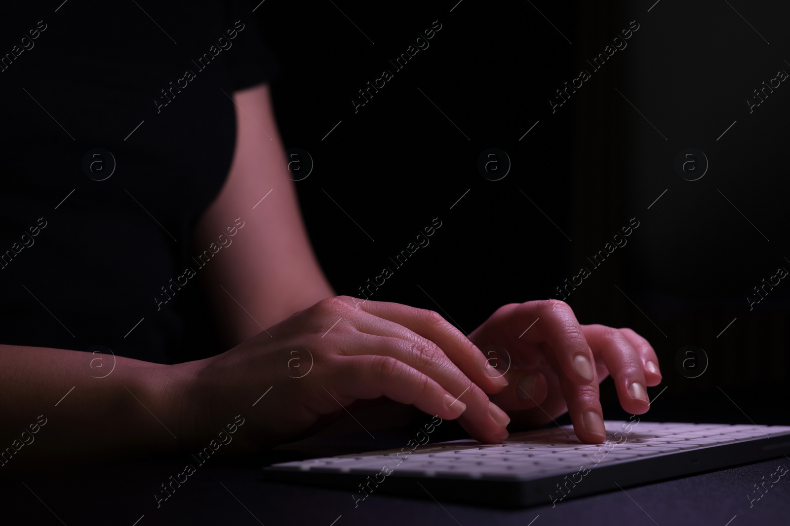 Photo of Woman using computer in dark room, closeup. Internet addiction