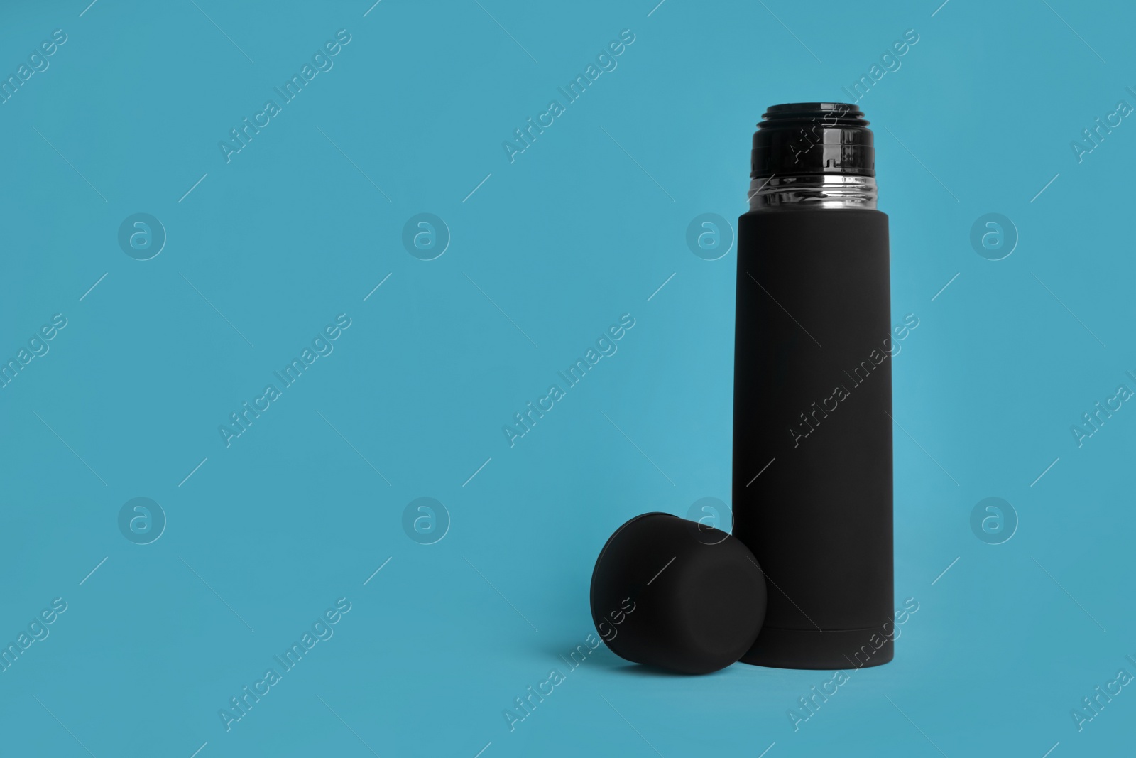 Photo of Stylish thermo bottle on light blue background, space for text