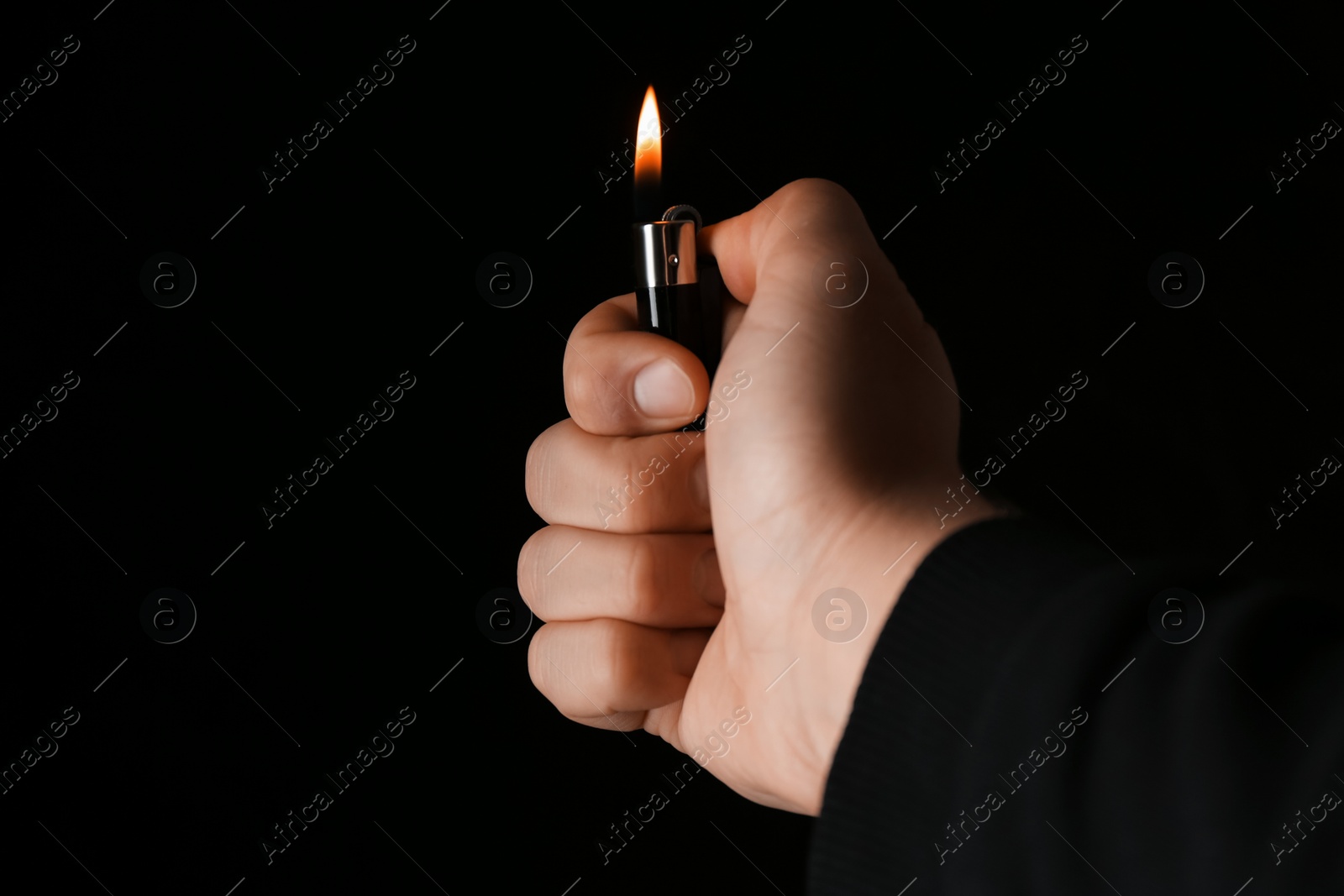 Photo of Man holding lighter on black background, closeup