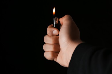 Photo of Man holding lighter on black background, closeup