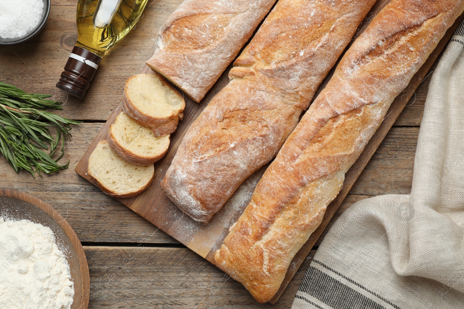 Photo of Delicious French baguettes on wooden table, flat lay