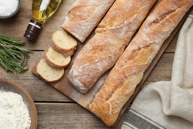 Photo of Delicious French baguettes on wooden table, flat lay