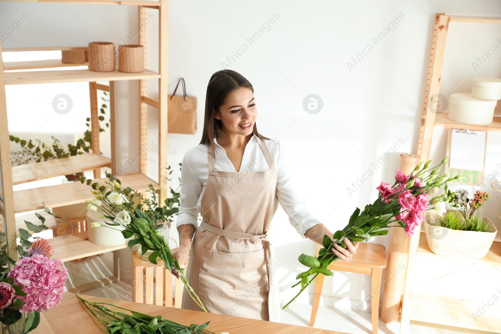 Photo of Florist making beautiful bouquet at table in workshop