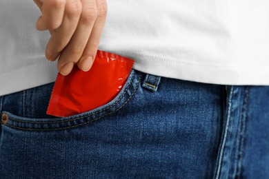Photo of Woman pulling condom out of pocket, closeup. Safe sex
