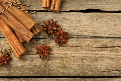 Photo of Cinnamon sticks and star anise on wooden table, flat lay. Space for text