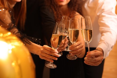 Photo of Friends with glasses of sparkling wine celebrating New Year, closeup