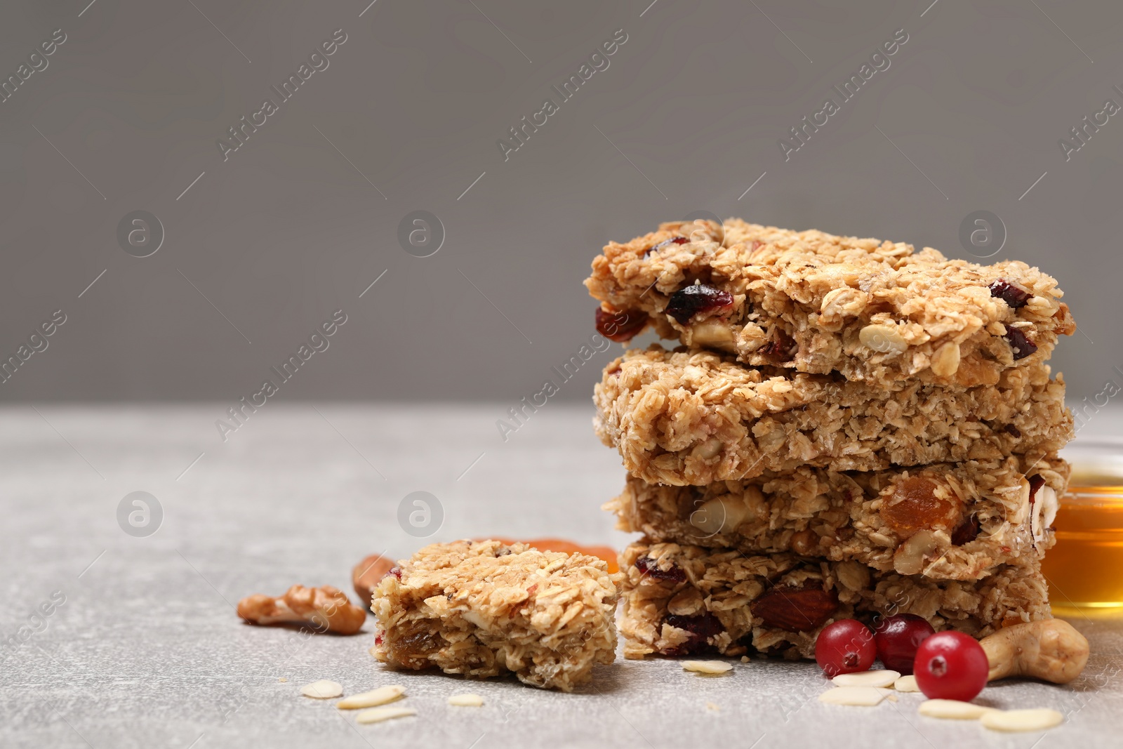 Photo of Stack of tasty granola bars on light grey table, closeup. Space for text