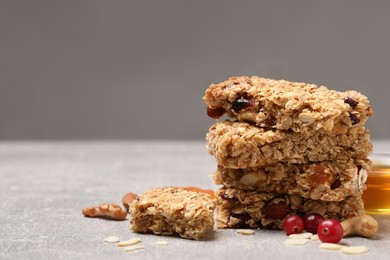 Photo of Stack of tasty granola bars on light grey table, closeup. Space for text