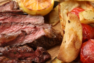 Delicious grilled beef with vegetables and lemon on table, closeup