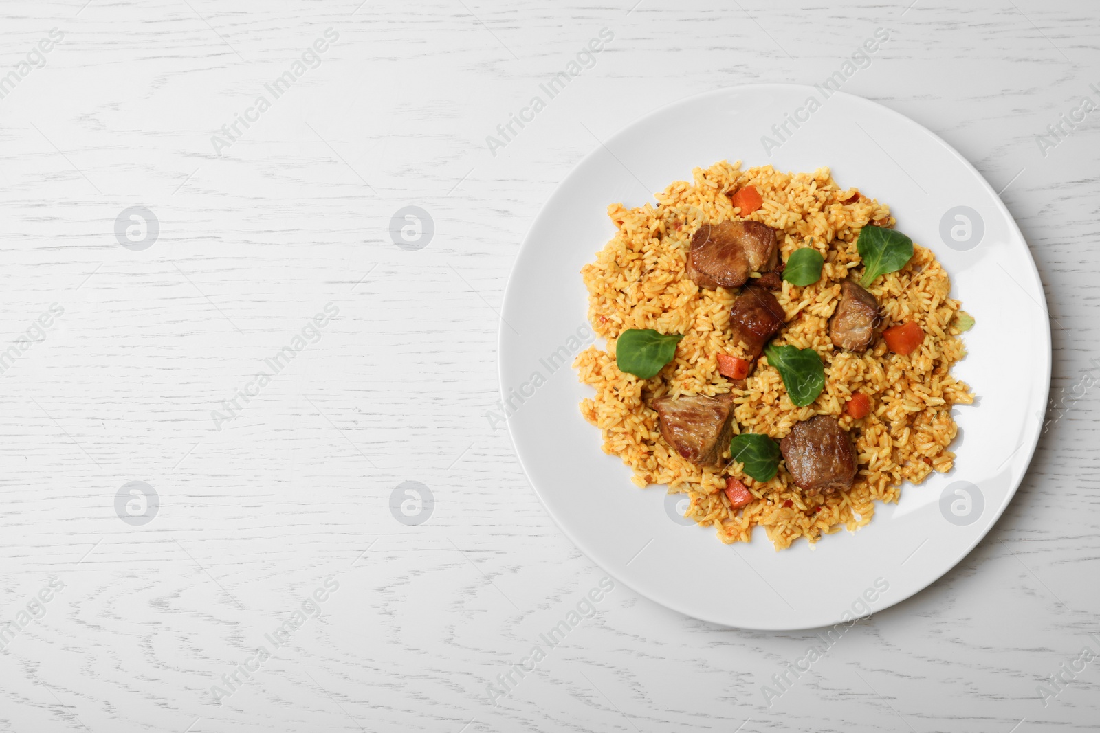 Photo of Plate of delicious rice pilaf on wooden background, top view with space for text