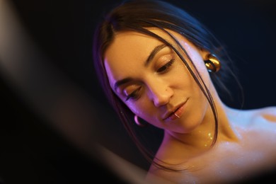 Photo of Portrait of beautiful woman on dark background in neon lights, view through ring lamp