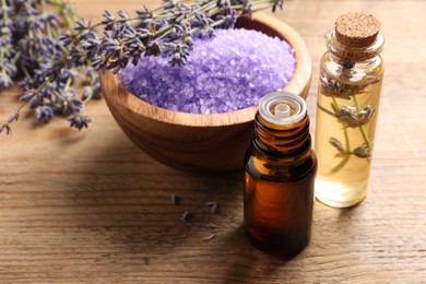 Bowl of sea salt, essential oil and lavender flowers on wooden table