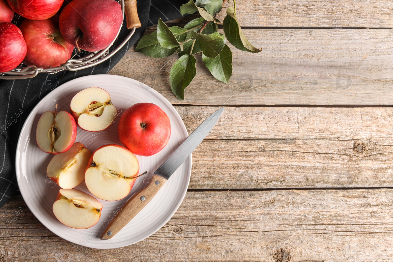 Photo of Fresh red apples, leaves and knife on wooden table, flat lay. Space for text