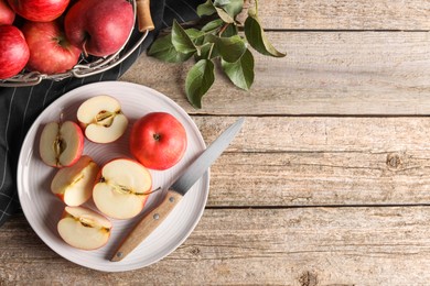 Photo of Fresh red apples, leaves and knife on wooden table, flat lay. Space for text