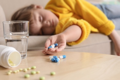 Unconscious little child with pills on sofa at home. Danger of medicament intoxication