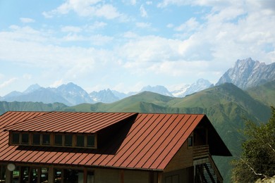Photo of View of building and mountains under bright cloudy sky