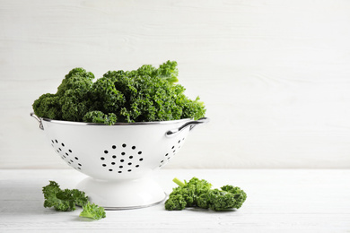 Fresh kale leaves on white wooden table. Space for text