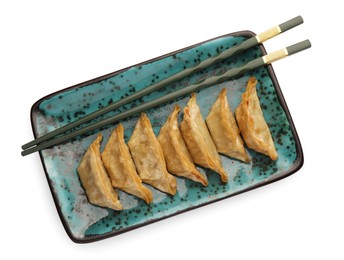 Photo of Delicious gyoza (asian dumplings) and chopsticks isolated on white, top view