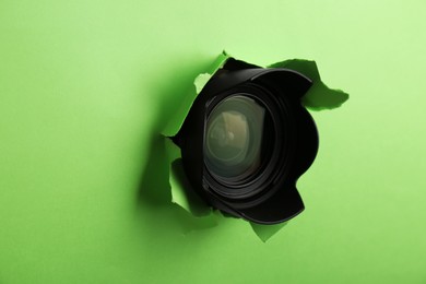 Photo of Hidden camera lens through torn hole in green paper