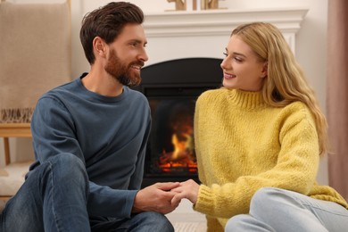 Lovely couple spending time together near fireplace indoors